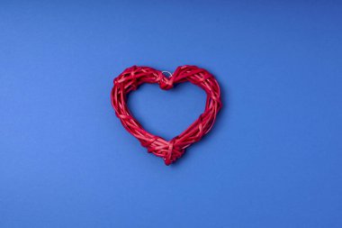 Mavi arka planda hasır kırmızı kalp. Boşluğu kopyala, düz yat, üst görünüm.