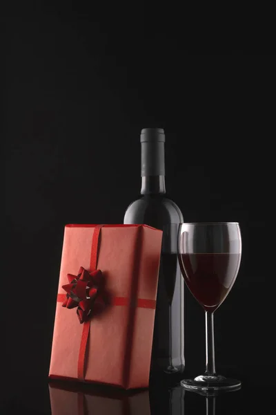 Confezione regalo, bottiglia di vino e bicchiere da vino su sfondo nero — Foto Stock
