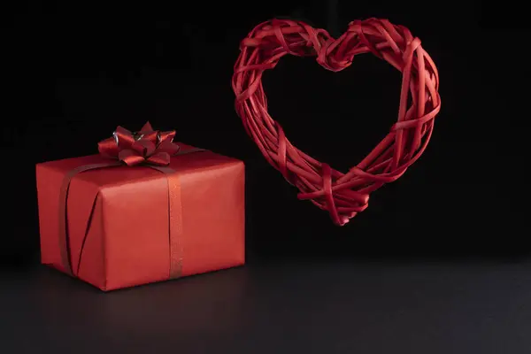 Концепция Дня Святого Валентина. Плетеные левитации красное сердце и подарочные коробки на черном фоне. Открытки, открытки — стоковое фото