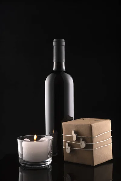 Caja de regalo, botella de vino, vela sobre fondo negro . — Foto de Stock