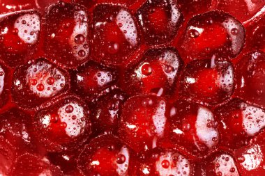 Pomegranate seeds close up background. Texture water drops on exotic fruit