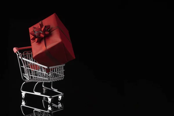 Shopping vagn vagn och presentförpackning på svart bakgrund. Köpa presenterar koncept, näthandel. — Stockfoto