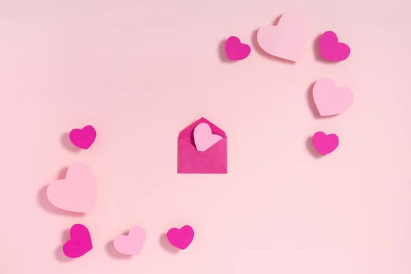 Конверт з любовним листом і сердечками валентинки на рожевій поверхні. Вид зверху, плоский ліжко — стокове фото
