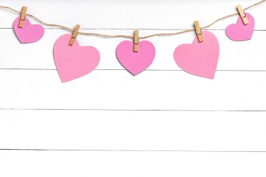 Pembe kalpli mandallar beyaz ahşap yüzeyin arkasında asılı..