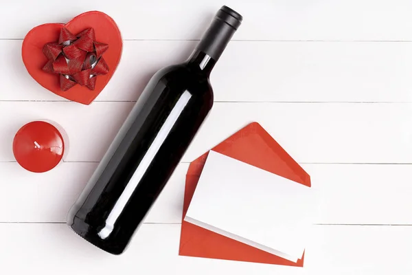 Heart, candle, wine bottle on white wooden surface. — Stock Photo, Image