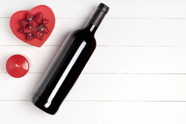 Cuore, candela, bottiglia di vino su superficie di legno bianca . — Foto Stock