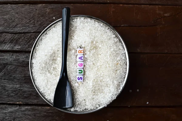 sugar text writing and black spoon on sugar,black background on
