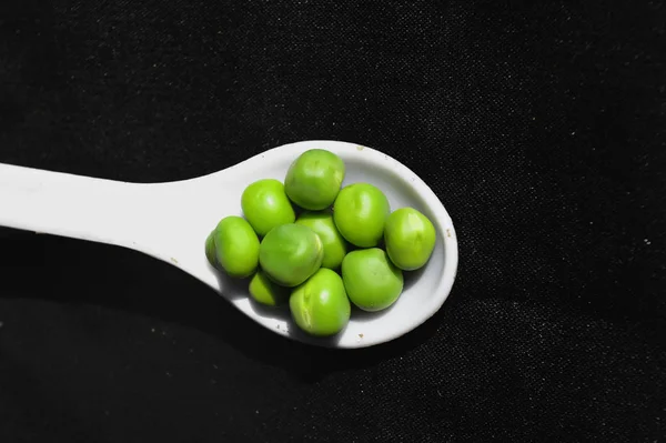 Frijoles de guisantes sobre fondo negro, cuchara blanca en frijoles de guisantes —  Fotos de Stock