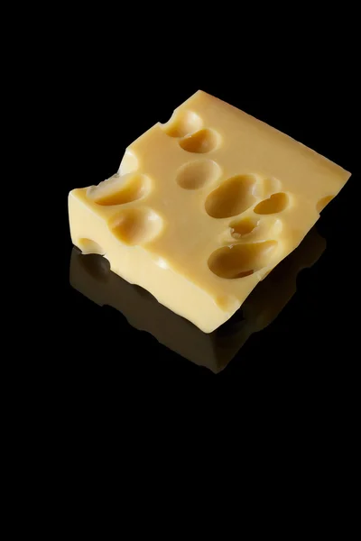 İsviçre peyniri siyah bir arka plan yansıması ile büyük delikli bir parça. minimalist tarzı gıda sanat. peynir portre