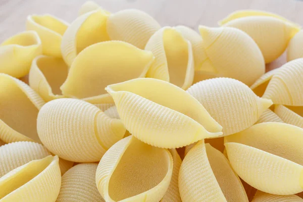 Klistra in i form av ett skal. råa italiensk pasta. bakgrunden mat — Stockfoto