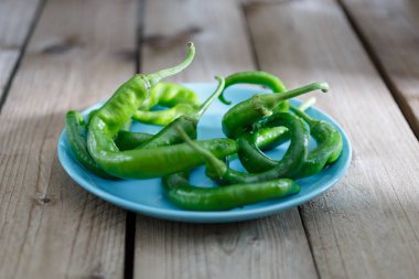 Bir ahşap zemin üzerinde mavi bir plaka üzerinde yeşil biber. Natürmort gıda tonlama ile resim