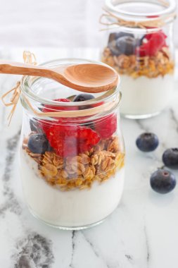 Alakart kahvaltı. Granola yoğurt, ahududu ve bir tahta kaşıkla bir bardak yaban mersini