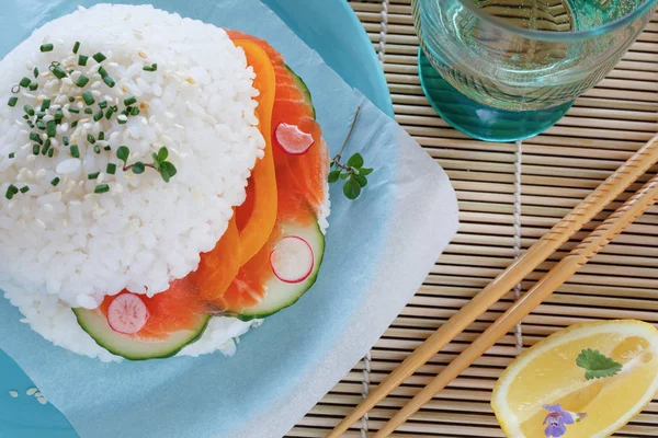 Pirinç, somon, salatalık ve biber mavi tabakta suşi burger. Fast food yeme parlak görüntü.