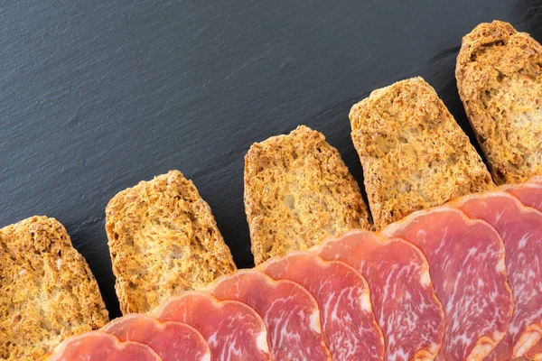 Rodajas de jamón español crudo lomo sobre pan crujiente rallado con cereales. Imagen de la vista de alimentos desde arriba . — Foto de Stock