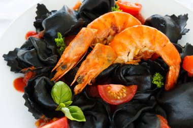 Siyah mürekkep mürekkep balığı domates, domates sosu ve beyaz bir tabak karides mantı. İtalyan mutfağı