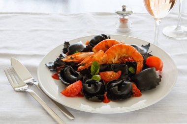 Siyah mürekkep mürekkep balığı domates, domates sosu ve beyaz bir tabak karides mantı. İtalyan mutfağı