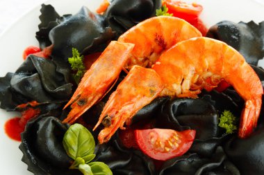 İtalyan Mantısı ile mürekkep mürekkep balığı, domates, beyaz bir tabak karides. Masaya yemek