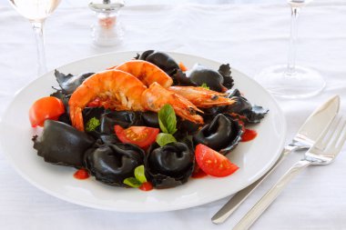 İtalyan Mantısı ile mürekkep mürekkep balığı, domates, beyaz bir tabak karides. Masaya yemek