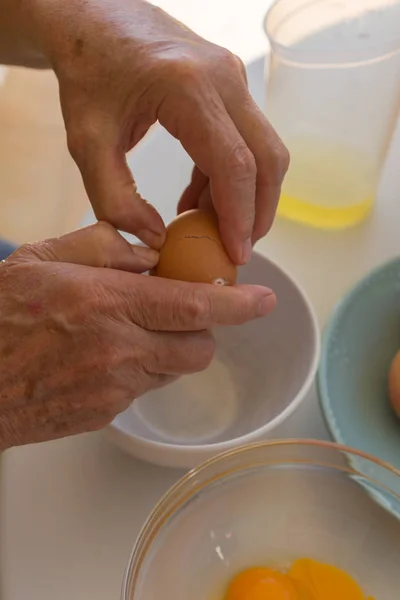 Разбитые яйца. Женские руки разбивают яйца на заднем столе с посудой — стоковое фото
