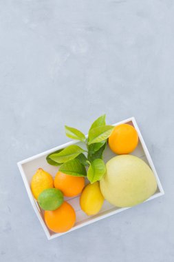 portakal, limon, limon bir gri doku arka plan üstten görünüm üzerinde yeşil yaprakları ile. karanlık bir arka plan üzerinde narenciye ile natürmort.