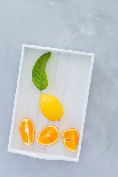 portakal, limon, limon bir gri doku arka plan üstten görünüm üzerinde yeşil yaprakları ile. karanlık bir arka plan üzerinde narenciye ile natürmort.