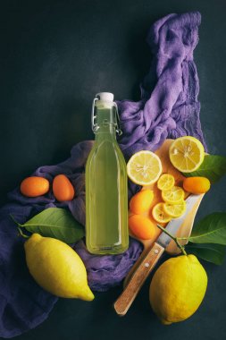 limonata karanlık bir arka plan üzerinde. Yaz geleneksel İtalyan ev yapımı içki Sicilya limon. düşük bir anahtar meyve ürünleri. eski arka plan resmi olan bir şişe içki mor kumaş arka plan ile.