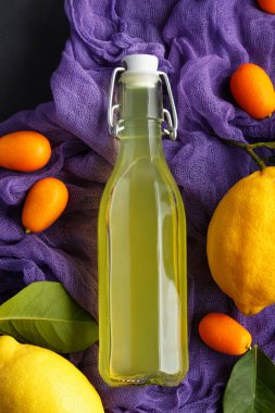 limonata karanlık bir arka plan üzerinde. Yaz geleneksel İtalyan ev yapımı içki Sicilya limon. düşük bir anahtar meyve ürünleri. eski arka plan resmi olan bir şişe içki mor kumaş arka plan ile.