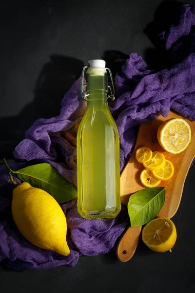 limonata karanlık bir arka plan üzerinde. Yaz geleneksel İtalyan ev yapımı içki Sicilya limon. düşük bir anahtar meyve ürünleri. eski arka plan resmi olan bir şişe içki mor kumaş arka plan ile.