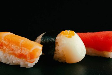somon, tarak ve tuna üzerinde siyah bir arka plan ile taze geleneksel suşi. suşi güzel resim.