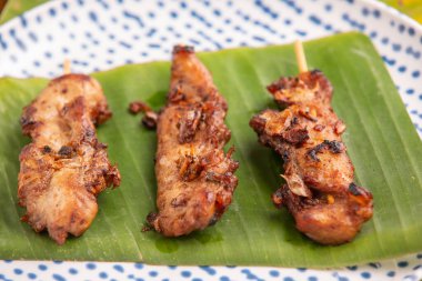 Izgara domuz şişi yere konur, yeşil muz kökü yaprakları...