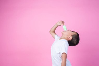 BOY EATING ICECREAM ON PINK BACKGROUND