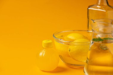 Sarı zemin üzerinde cam kaplar olan taze limon ürünleri.