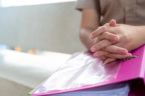 picture of closed up hands clasped on a pink file