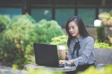 Kafede dizüstü bilgisayarda çalışan ve kahve içen bir kadın.
