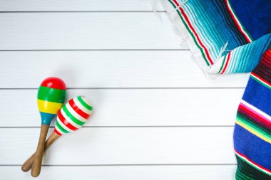 Mexican maraca and colorful blanket on wooden floor
