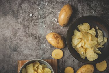 Siyah tabakta patates cipsi ve gri arka planda patates cipsi.