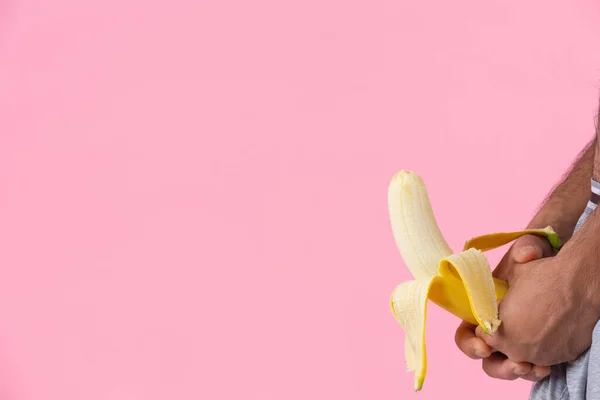 A man with a standing gesture holding a banana on the pink background