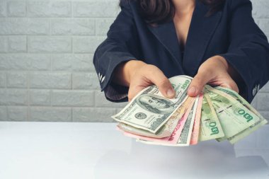 Kadın çalışanlar beyaz bir masada para sayıyor.