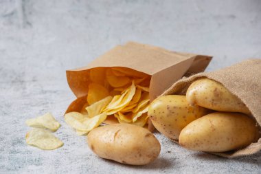 Gri zemindeki çuvallardan patatesler dökülüyor. 