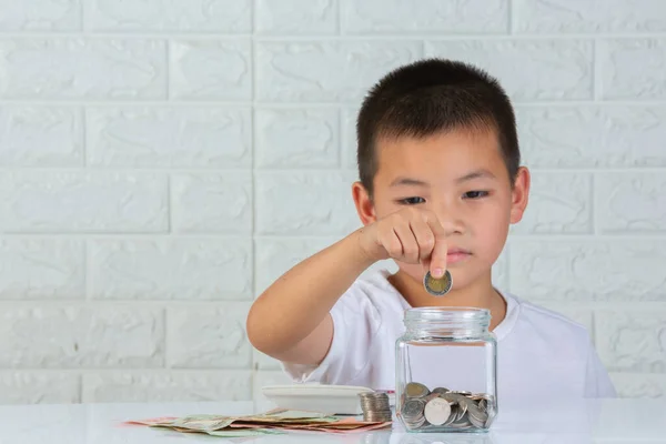 a boy drop coin in to the jar on white background