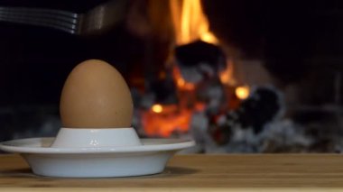 Yumurta. Basit bir yemek. Bir adam şöminenin arka planında duran çay kaşığıyla yumurta kırar. Kapat..