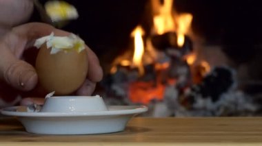Basit bir yemek. Bir insan, şöminenin arka planında duran çay kaşığıyla yumurta yer. Kapat..