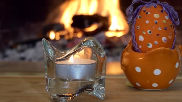 イースター休暇 暖炉の炎を背景にろうそくの横に立つ人工イースターエッグ — ストック動画