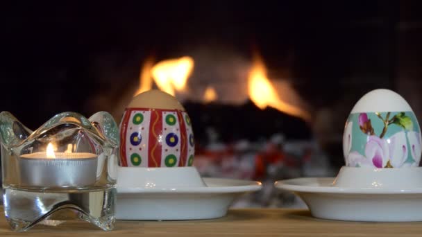 复活节假期 五彩斑斓的鸡蛋躺在壁炉边的蜡烛旁边 — 图库视频影像