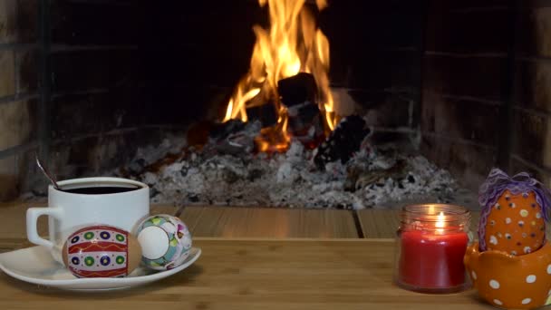 复活节假期 五彩斑斓的鸡蛋躺在茶匙旁边的茶匙盘上 烛光映衬着壁炉的火焰 — 图库视频影像