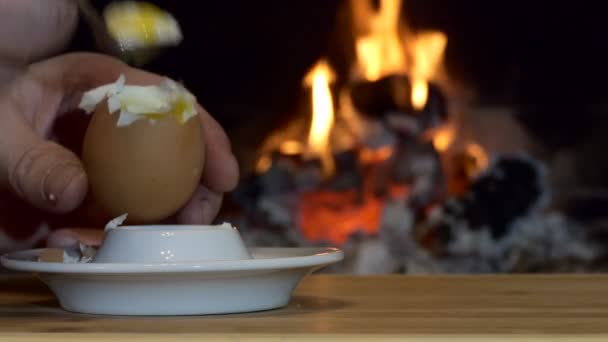 简单的晚餐 一个人在壁炉火焰的背景下吃着一个有茶匙的鸡蛋 茶匙放在架子上 靠近点 — 图库视频影像