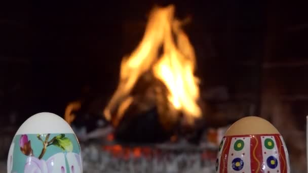 イースター休暇 多色の卵が暖炉の炎の背景に立っている ズーム — ストック動画
