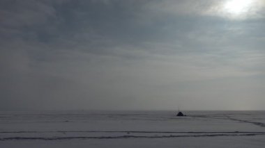 Kışın balık. Sibirya 'daki donmuş Ob nehrinin buzunda ocağı olan balıkçı çadırı. Genel plan. Arka ışıklandırma.