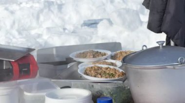 Basit bir yemek. Aşçı, evin dışındaki ocakta pişmiş karabuğday lapası ile bir tepsi tabağı koyar. Sibirya.