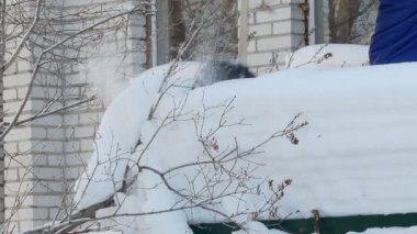 Kar temizliği. Adamın biri kar küreğiyle evin garajından kar dökmek için merdivenleri çıkıyor. Sibirya 'da. kaybet.